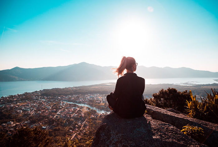 Person sitting on a mountain overlooking a serene landscape, symbolizing aftercare and grief support offered by East Lawn in Sacramento. This image represents guidance, help, and emotional support for those touched by grief.