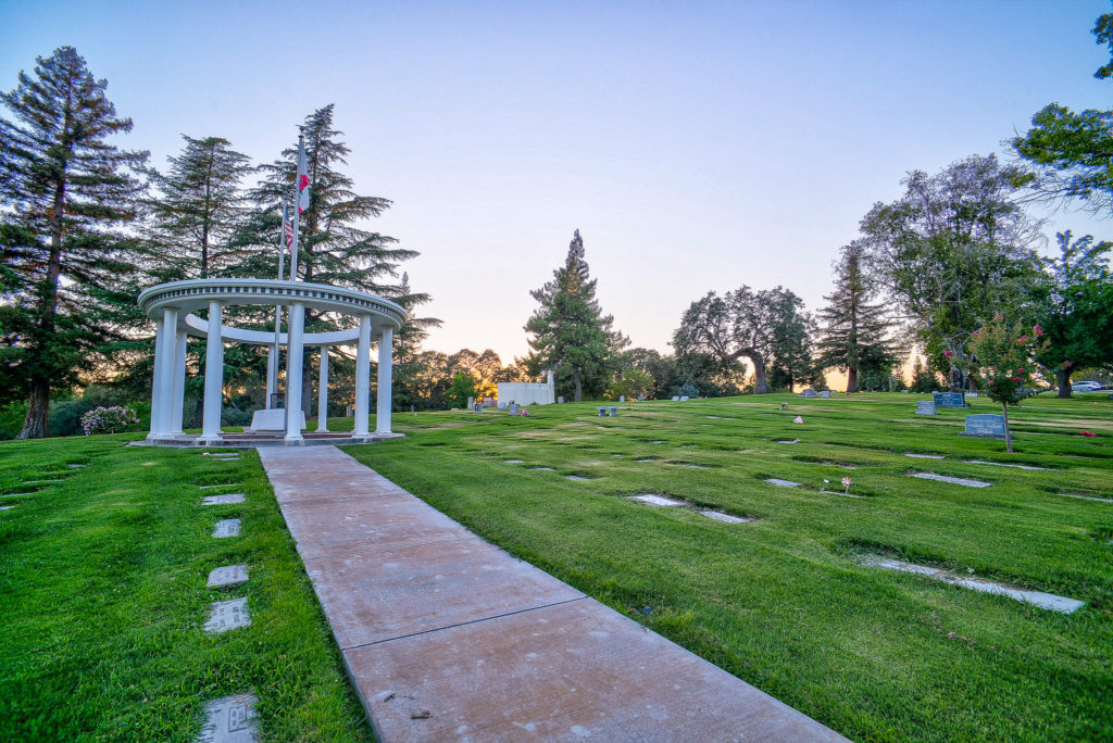 Quiet cemetery scene with a paved walkway leading to a the Veteran's Memorial site.